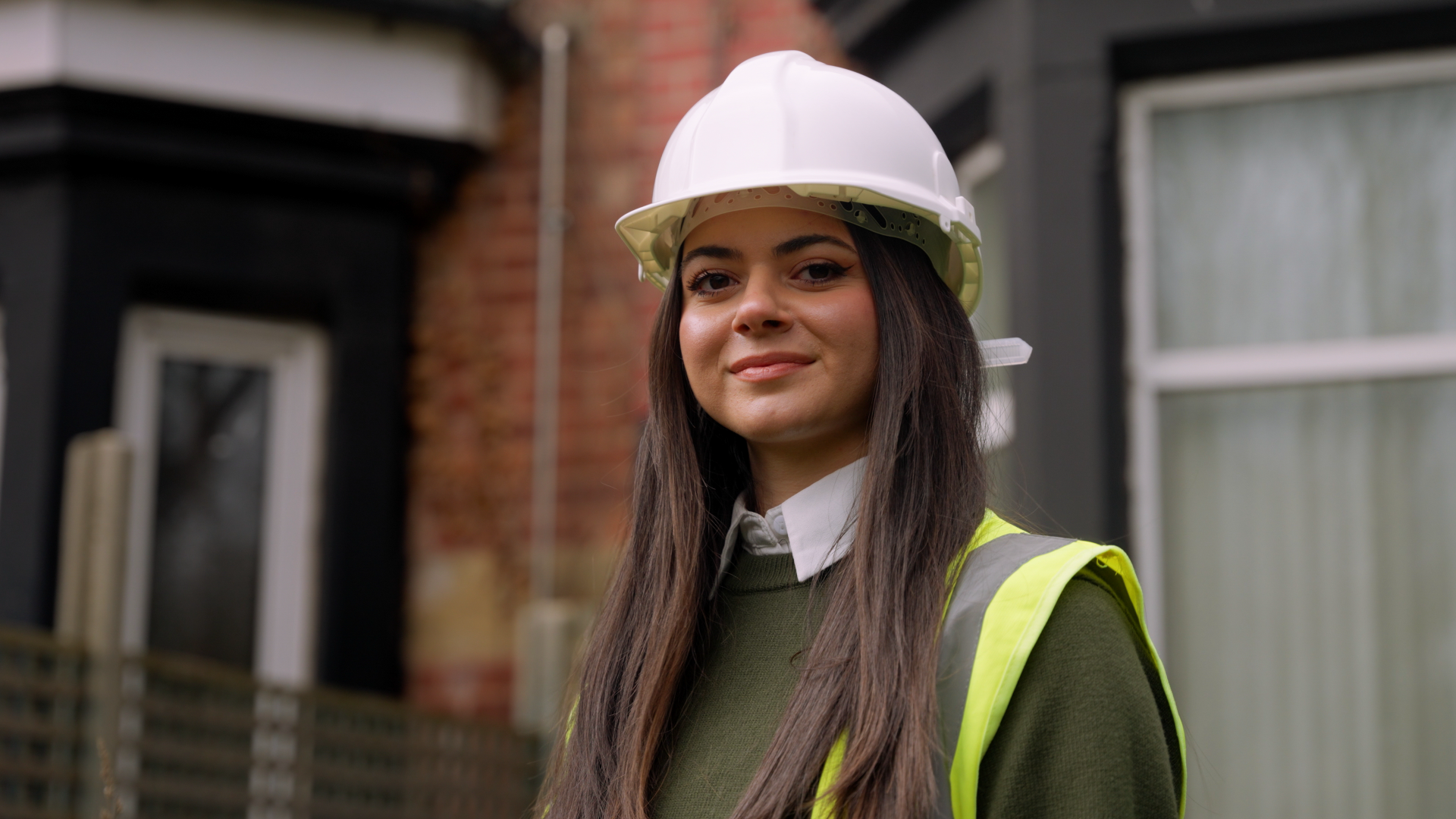 Lana on site in a hard hat and hi-vis vest, smiling at the camera