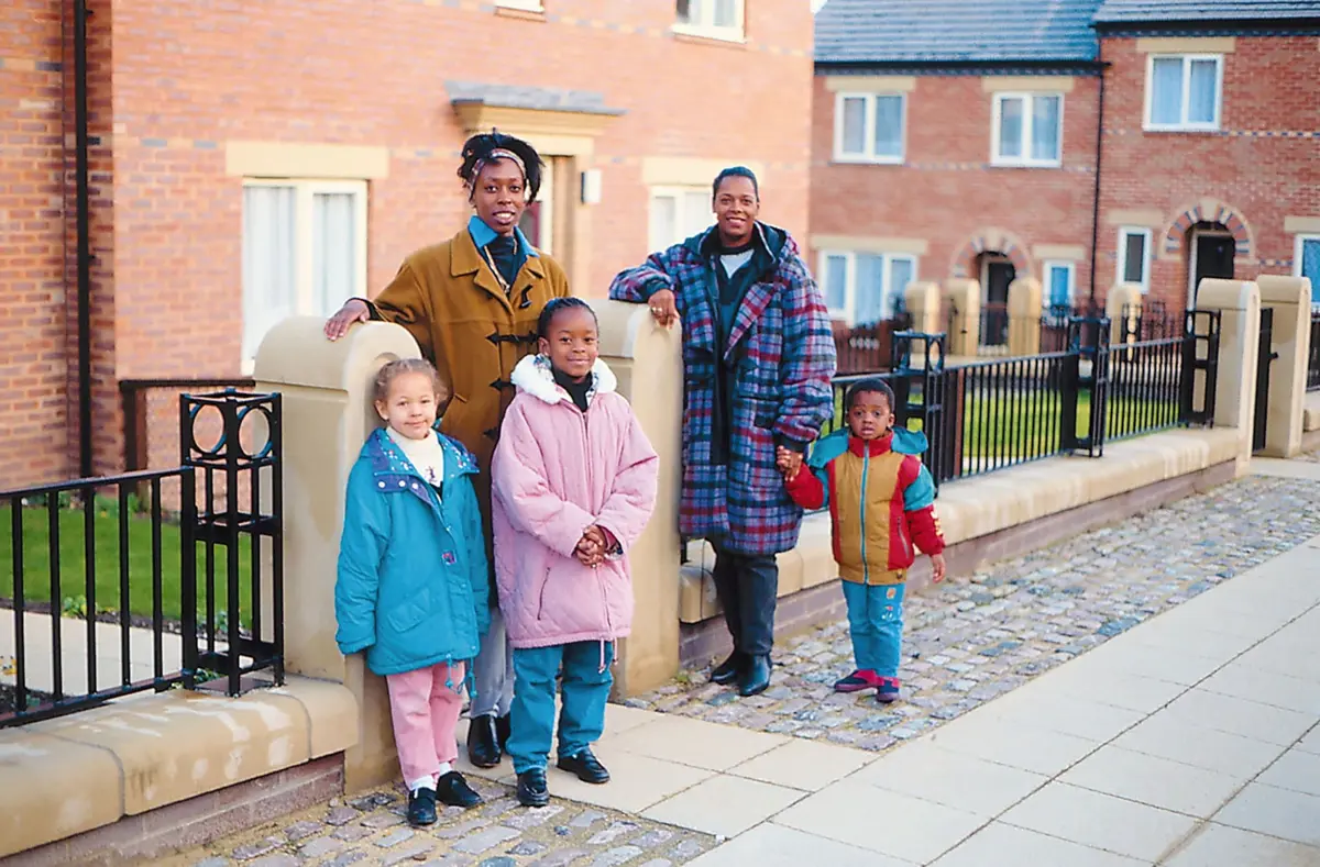 A family of five smiling outside their new-build home
