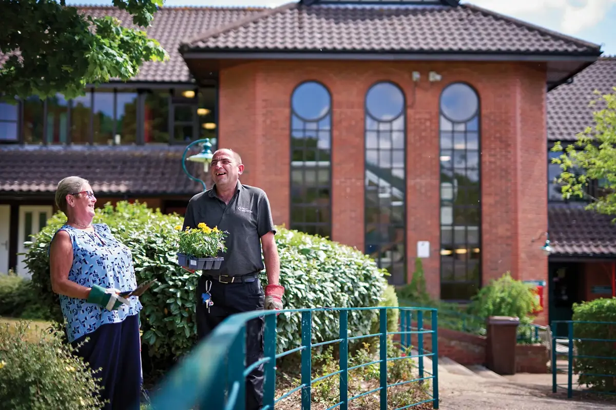 A gardener and a resident laughing together over a potted plant