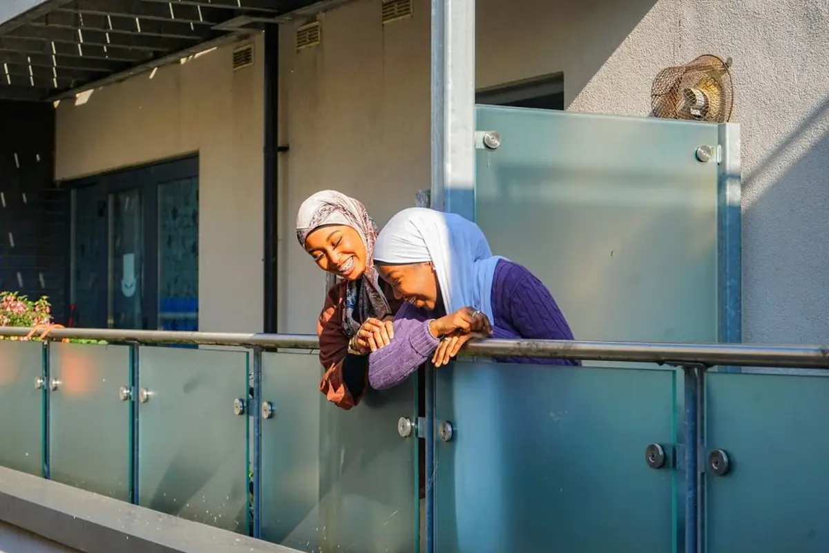 Two neighbours leaning over their balcony, deep in conversation